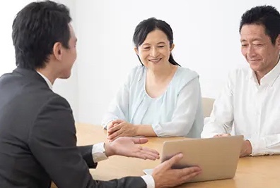 スーツを着ている人に相談をして笑顔になる夫婦の写真